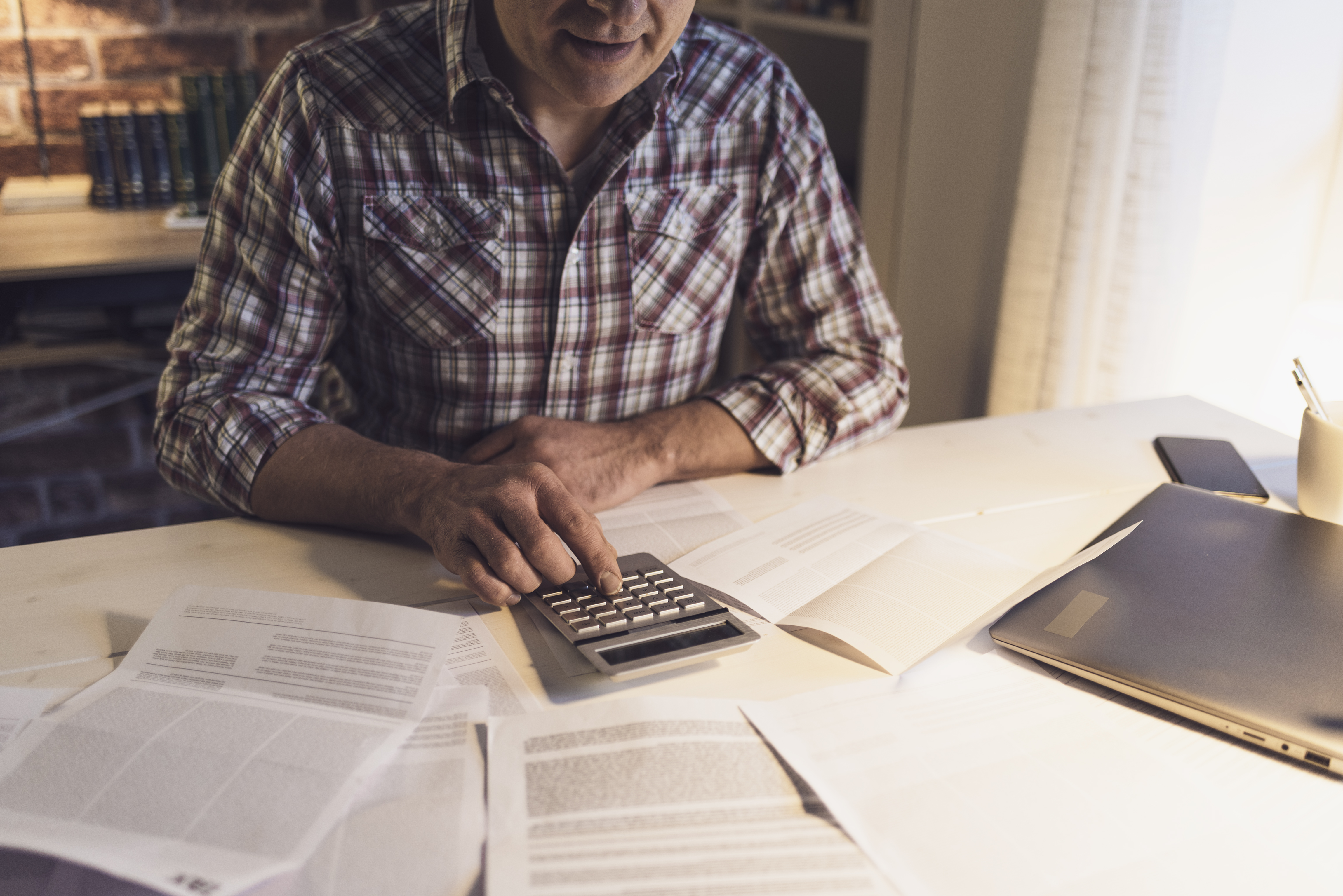 Mand ved skrivebord med en masse papirer og en lommeregner